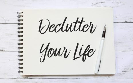 Top view of pen and notebook written with Declutter Your Life on wooden background.