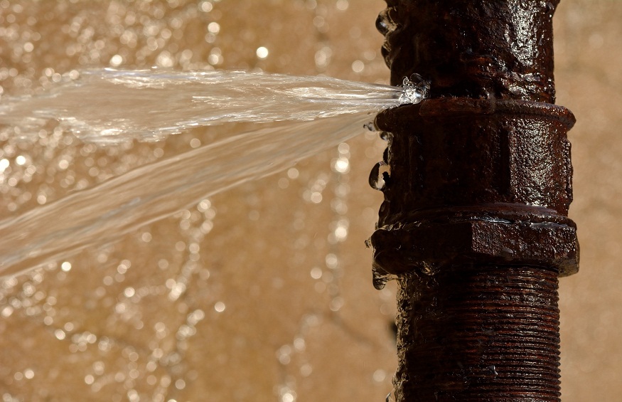 Rusty burst pipe squirting water at high pressure