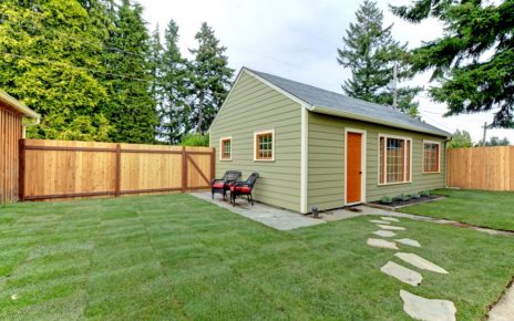 Small green guest houe in the fenced back yard.