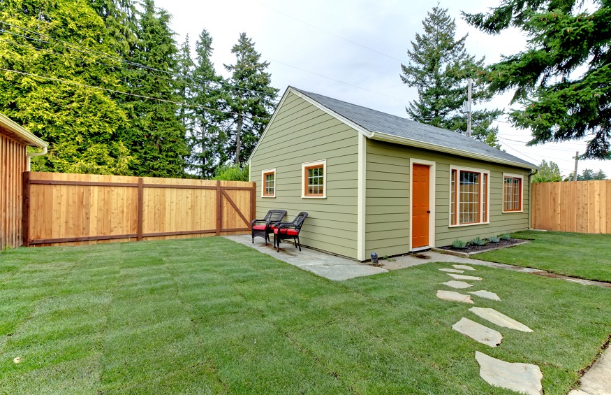 Small green guest houe in the fenced back yard.